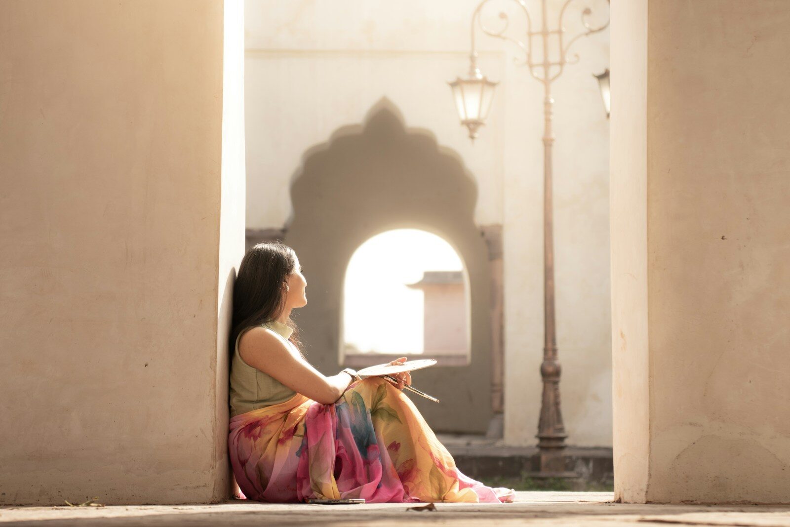 A woman in a colorful sari sits and draws.